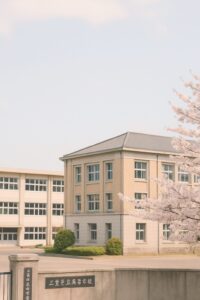 三重県の県立高校の校舎と桜の花が咲く春の風景。2026年度の定員削減に関連するイメージ。