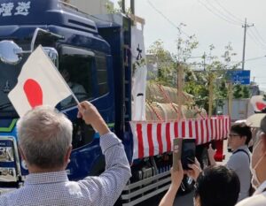 桑名市で行われた伊勢神宮式年遷宮の御樋代木奉送行事で、トラックに乗せられた神木を市民が日の丸を振って見送る様子