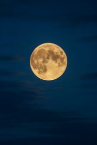 雲間から昇る黄金色の満月が、夏の夜空に美しく浮かぶ