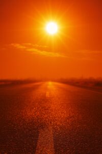 真夏の太陽が照りつけるアスファルト道路と揺らめく熱気の風景